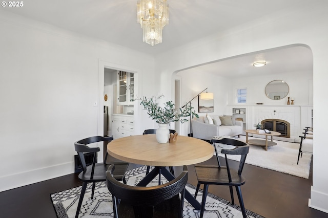 dining area with wood-type flooring, a fireplace, and a chandelier