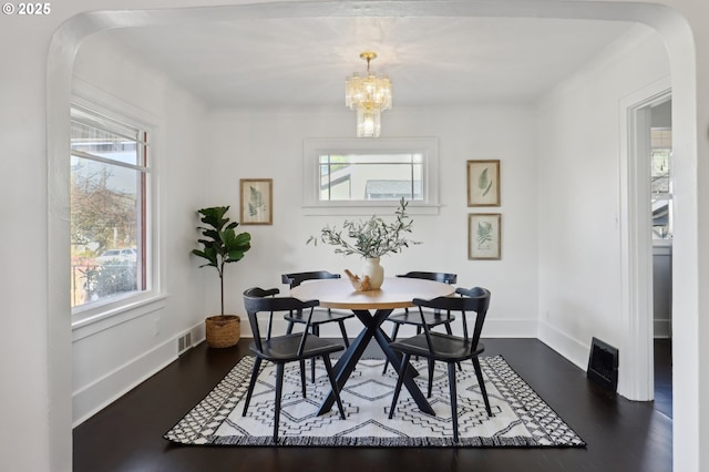 dining area with dark hardwood / wood-style floors, plenty of natural light, and a notable chandelier