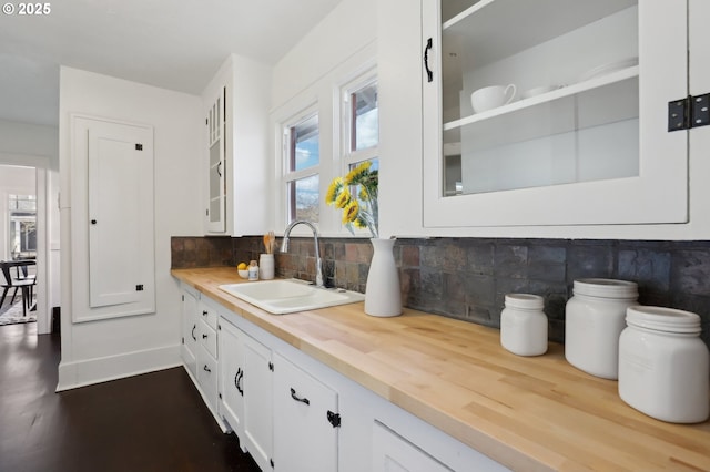 kitchen featuring white cabinets, backsplash, wooden counters, and sink