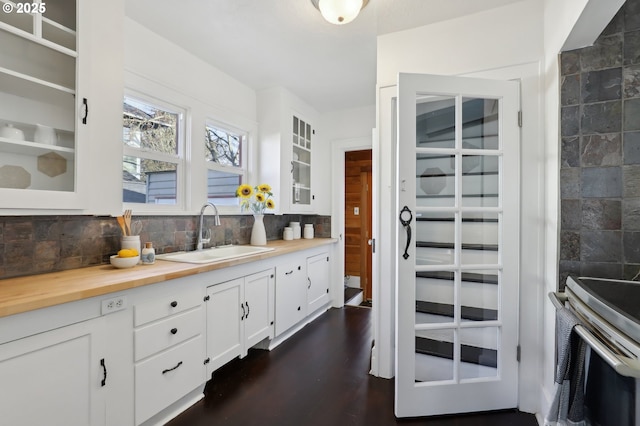 interior space featuring butcher block counters, sink, dark hardwood / wood-style floors, backsplash, and white cabinets