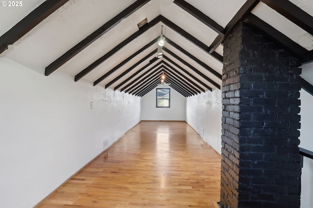 additional living space featuring vaulted ceiling with beams and light hardwood / wood-style flooring