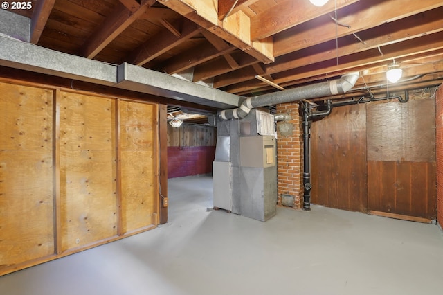 basement with heating unit and wood walls