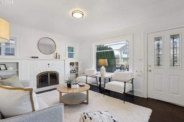 living room with dark wood-type flooring and a brick fireplace