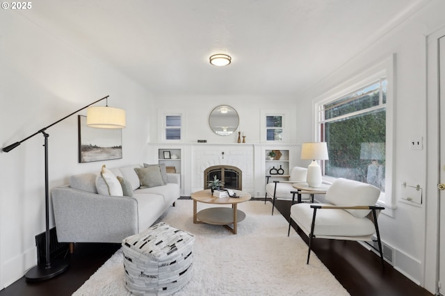 living room with hardwood / wood-style flooring and a brick fireplace