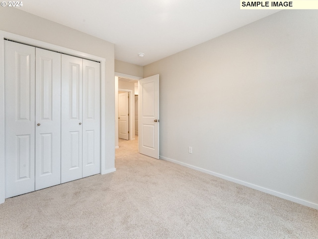 unfurnished bedroom with light carpet and a closet