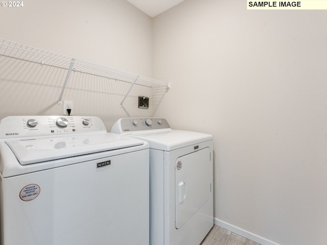 laundry room with separate washer and dryer and light hardwood / wood-style flooring