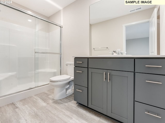 bathroom featuring hardwood / wood-style flooring, vanity, toilet, and an enclosed shower