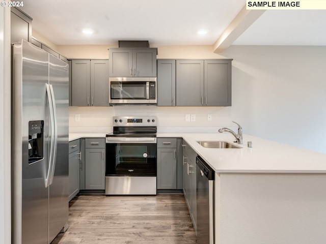 kitchen featuring stainless steel appliances, light hardwood / wood-style flooring, gray cabinetry, and sink