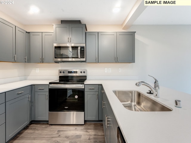 kitchen featuring gray cabinets, sink, wood-type flooring, and stainless steel appliances