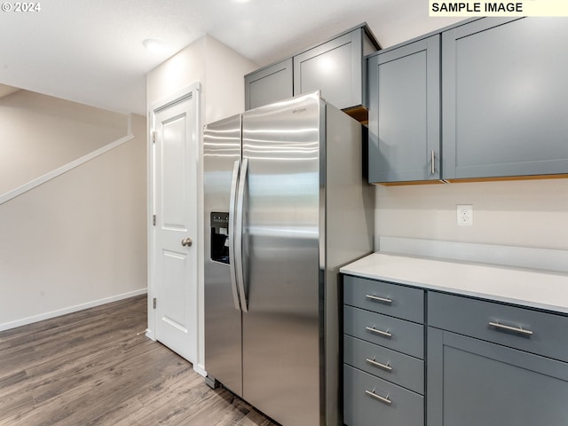 kitchen featuring gray cabinets, stainless steel fridge, and light wood-type flooring