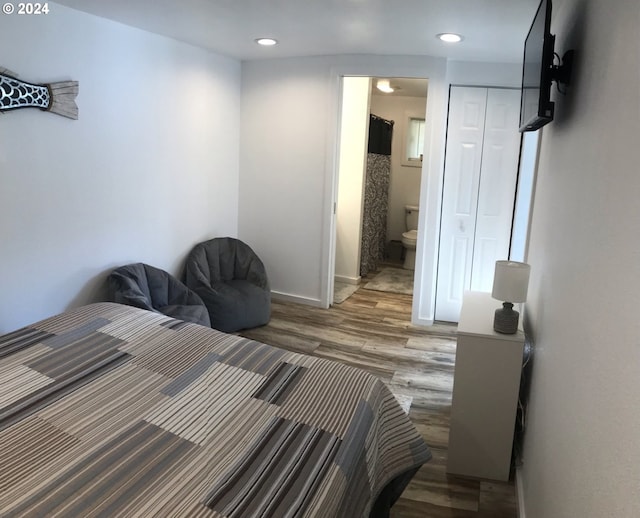 bedroom featuring hardwood / wood-style flooring, ensuite bathroom, and a closet