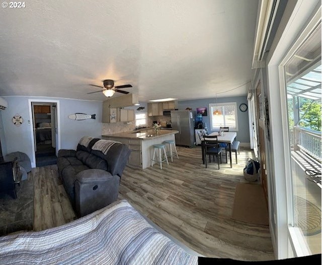 living room with ceiling fan, wood-type flooring, and an AC wall unit