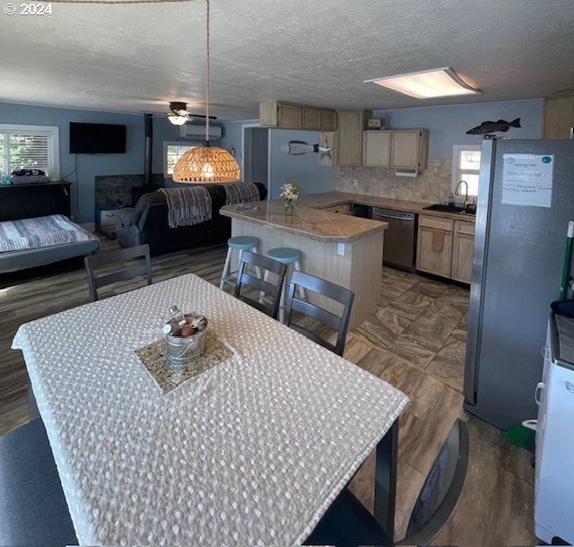 kitchen featuring pendant lighting, light brown cabinets, ceiling fan, a textured ceiling, and appliances with stainless steel finishes