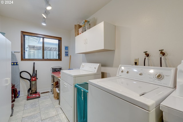 laundry room with cabinets, separate washer and dryer, and rail lighting