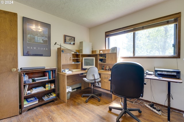 office area featuring light wood-type flooring, a textured ceiling, and a wealth of natural light