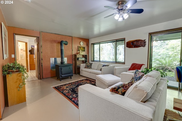 living room featuring a wood stove and ceiling fan