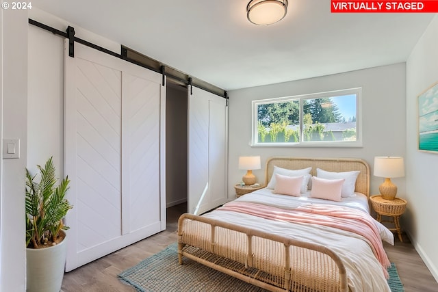 bedroom featuring a barn door and light hardwood / wood-style flooring