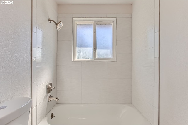 bathroom featuring toilet and tiled shower / bath combo