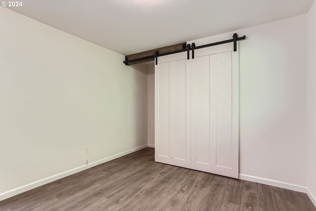 unfurnished bedroom featuring a barn door and wood-type flooring