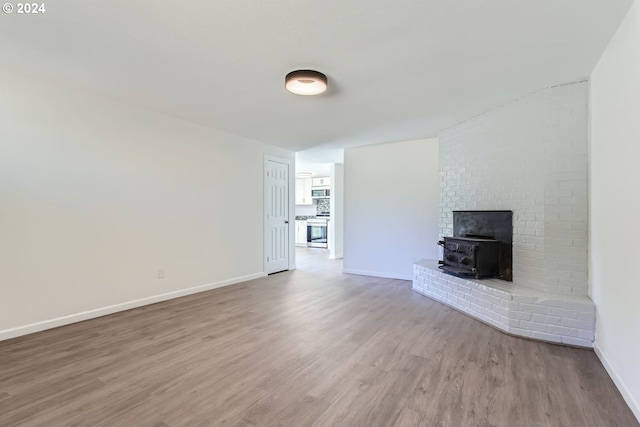 unfurnished living room featuring hardwood / wood-style flooring and a wood stove