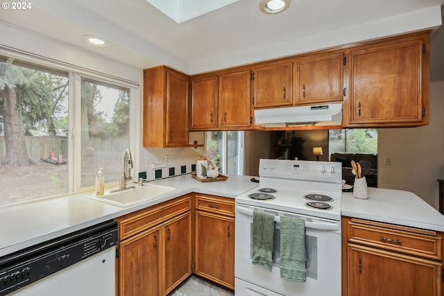 kitchen with white appliances, sink, a skylight, and kitchen peninsula