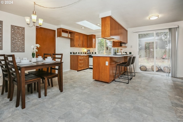 kitchen with hanging light fixtures, kitchen peninsula, dishwasher, a skylight, and a notable chandelier