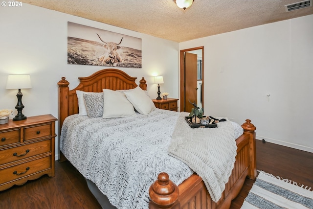 bedroom with a textured ceiling and dark wood-type flooring