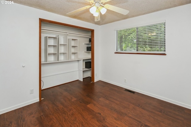 unfurnished bedroom with ceiling fan, a textured ceiling, a closet, and dark hardwood / wood-style flooring