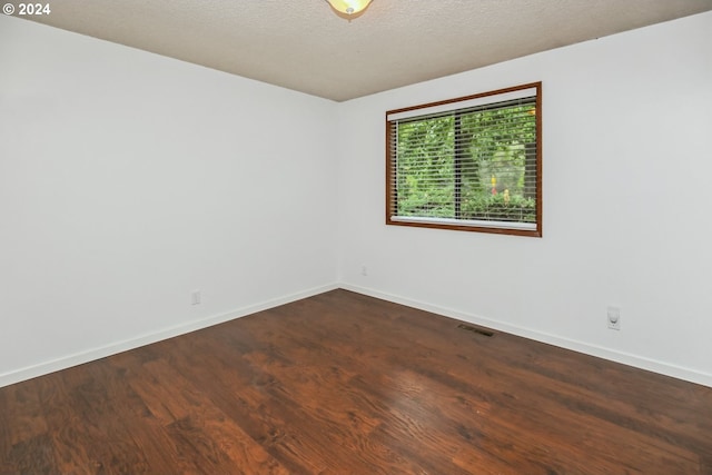 spare room featuring a textured ceiling and dark hardwood / wood-style floors