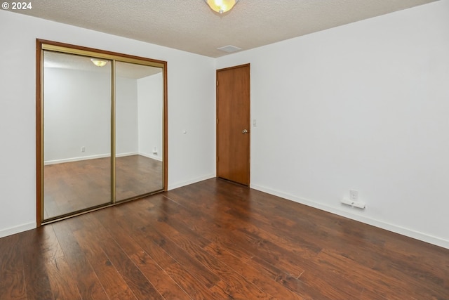 unfurnished bedroom with a closet, dark hardwood / wood-style floors, and a textured ceiling