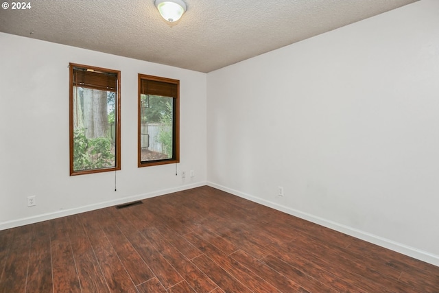 empty room with a textured ceiling and dark wood-type flooring