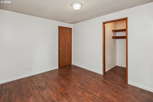 unfurnished bedroom featuring a textured ceiling, a closet, and dark hardwood / wood-style floors