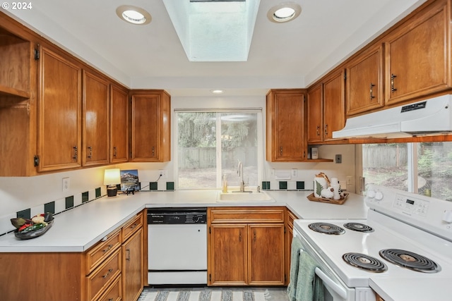 kitchen featuring a skylight, sink, white appliances, and a wealth of natural light