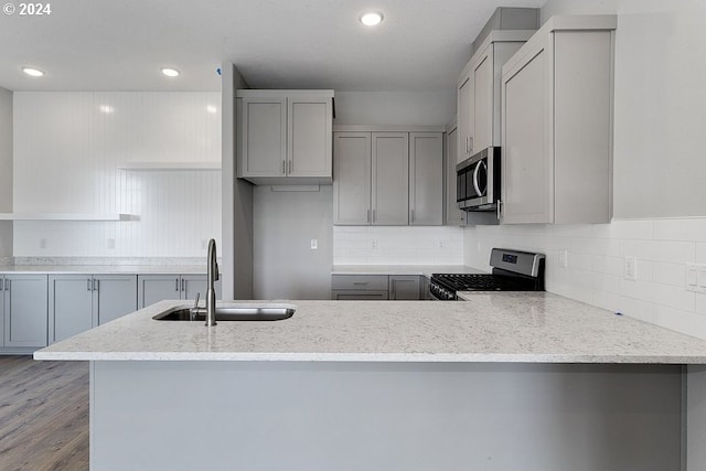 kitchen featuring kitchen peninsula, light wood-type flooring, gray cabinetry, stainless steel appliances, and sink