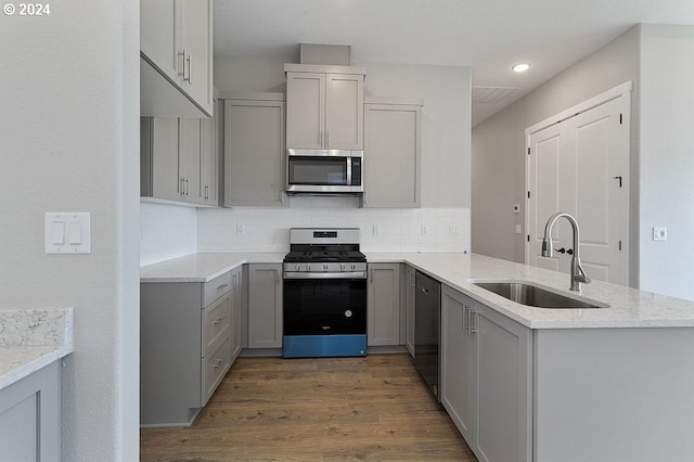 kitchen with sink, gray cabinets, appliances with stainless steel finishes, tasteful backsplash, and dark hardwood / wood-style flooring