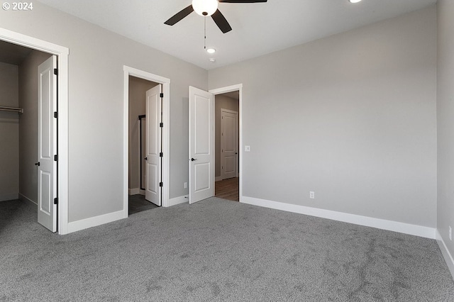 unfurnished bedroom with dark colored carpet, a spacious closet, and a closet