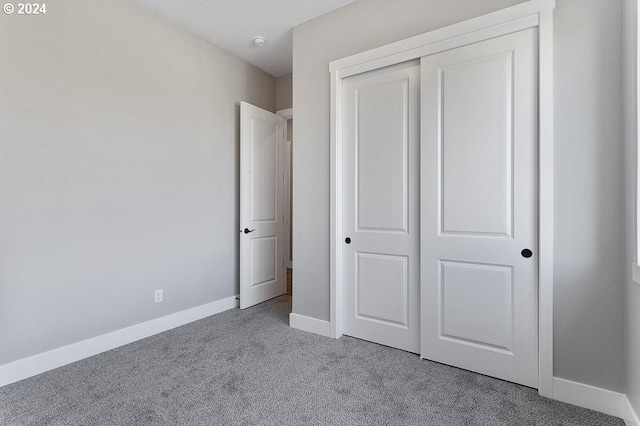 unfurnished bedroom featuring light carpet and a closet