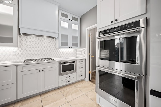 kitchen featuring appliances with stainless steel finishes, light tile patterned floors, decorative backsplash, and white cabinetry