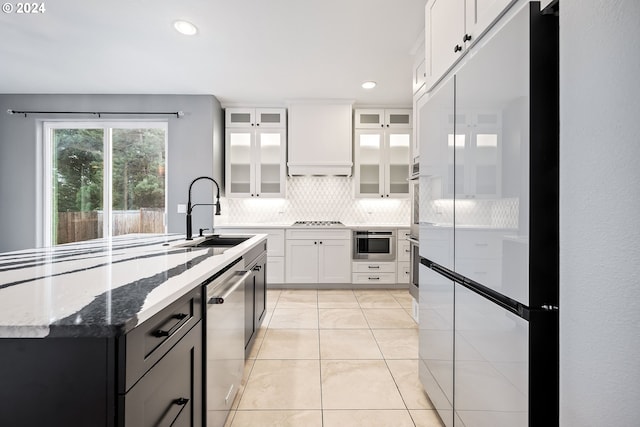 kitchen with premium range hood, sink, white cabinetry, dark stone counters, and stainless steel appliances