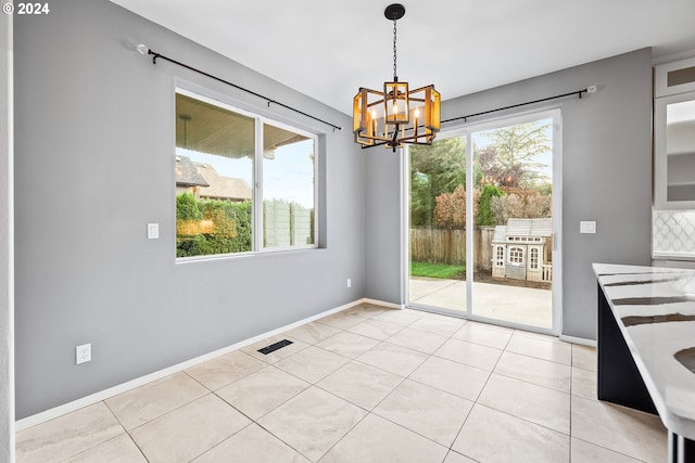 unfurnished dining area featuring plenty of natural light, light tile patterned floors, and a chandelier