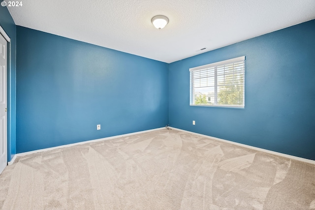 spare room featuring a textured ceiling and carpet