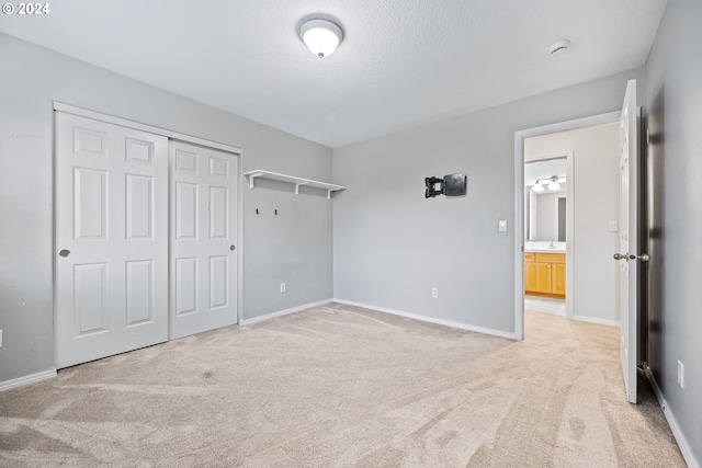 unfurnished bedroom with light colored carpet, a textured ceiling, a closet, and sink