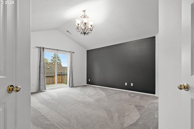 carpeted empty room featuring vaulted ceiling and a notable chandelier