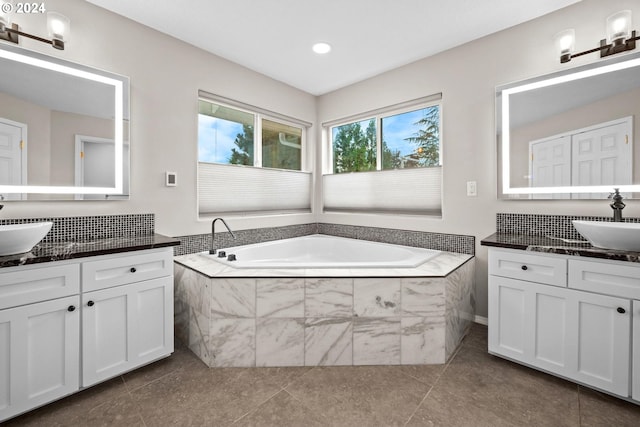 bathroom featuring a relaxing tiled tub, vanity, and tile patterned flooring