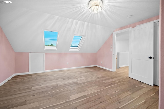 bonus room featuring light wood-type flooring and lofted ceiling with skylight