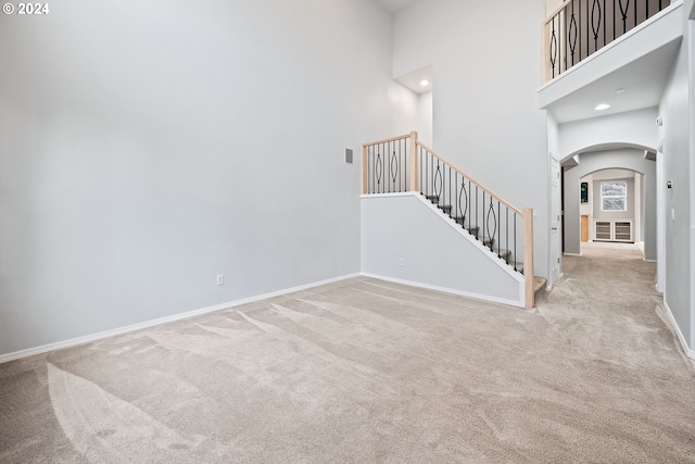 unfurnished room featuring light colored carpet and a high ceiling