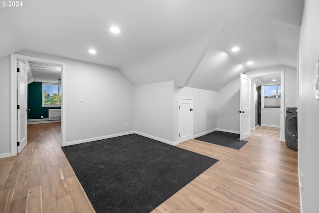 additional living space with washer / clothes dryer, vaulted ceiling, and light hardwood / wood-style flooring