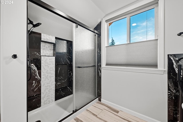 bathroom with walk in shower, lofted ceiling, and hardwood / wood-style floors