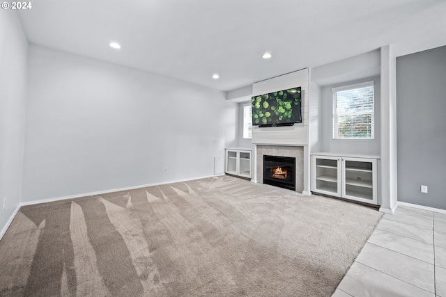 unfurnished living room with light colored carpet and a tiled fireplace