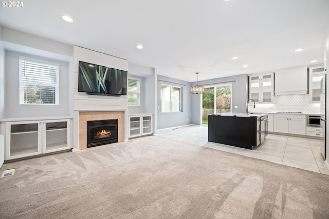 unfurnished living room featuring light colored carpet, plenty of natural light, a fireplace, and sink